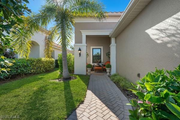 doorway to property featuring a yard and stucco siding