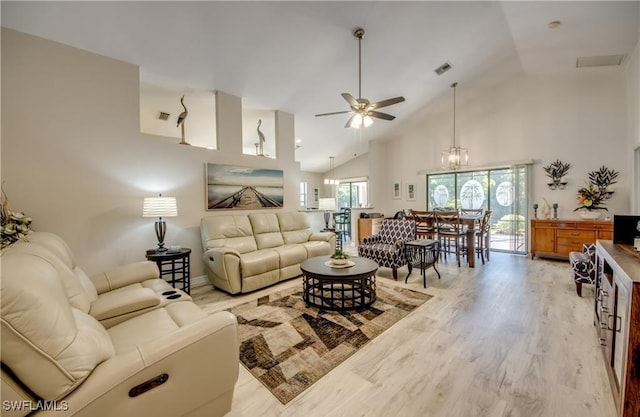 living room featuring light wood-type flooring, visible vents, high vaulted ceiling, and ceiling fan with notable chandelier