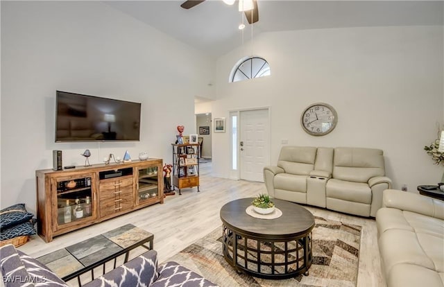 living area with high vaulted ceiling, light wood-type flooring, and a ceiling fan