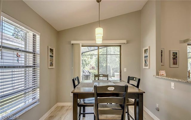 dining room with baseboards, light wood-style floors, and vaulted ceiling