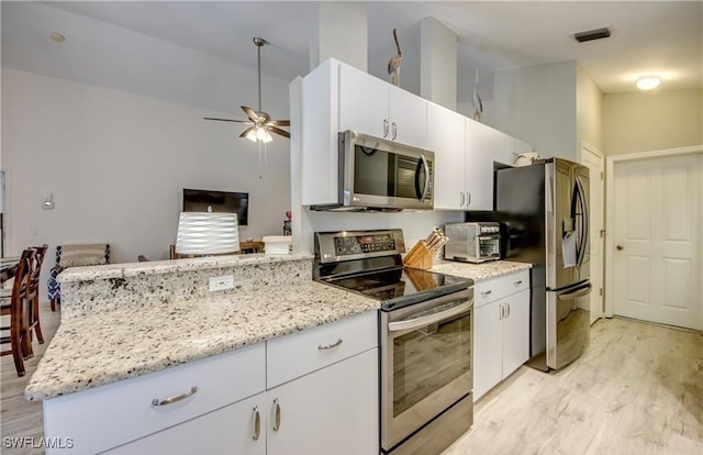 kitchen featuring light wood finished floors, white cabinetry, stainless steel appliances, and a ceiling fan