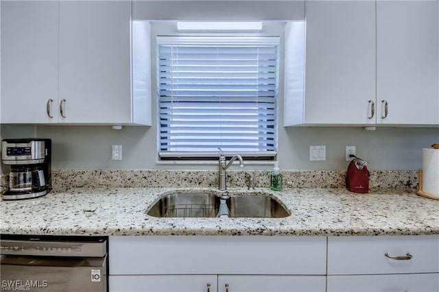 kitchen with a sink, light stone countertops, dishwasher, and white cabinets