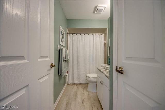 full bath with visible vents, curtained shower, toilet, wood finished floors, and vanity