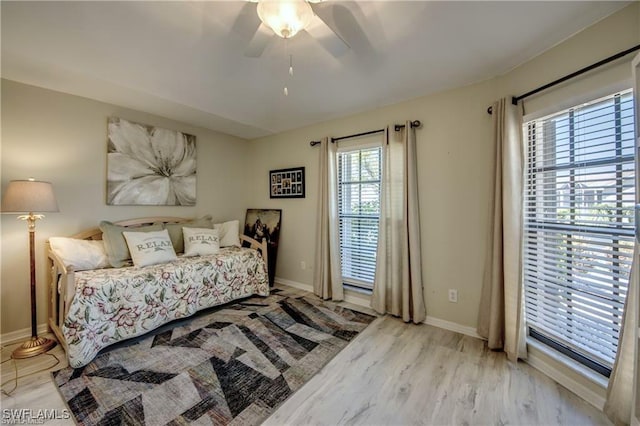 bedroom featuring baseboards, wood finished floors, a ceiling fan, and access to exterior