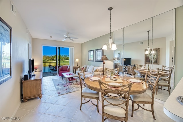 dining area featuring light tile patterned floors, ceiling fan with notable chandelier, visible vents, and baseboards