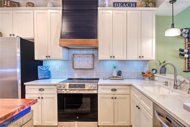 kitchen with white cabinetry, stainless steel appliances, exhaust hood, and a sink