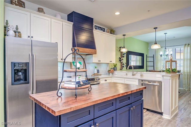 kitchen with a sink, wood counters, appliances with stainless steel finishes, and white cabinetry