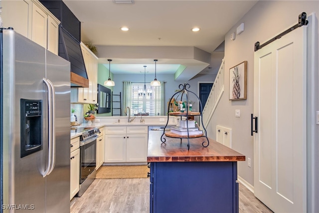 kitchen with light wood-style flooring, a sink, butcher block countertops, appliances with stainless steel finishes, and a barn door