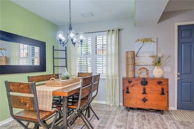 dining area with baseboards, an inviting chandelier, and wood finished floors