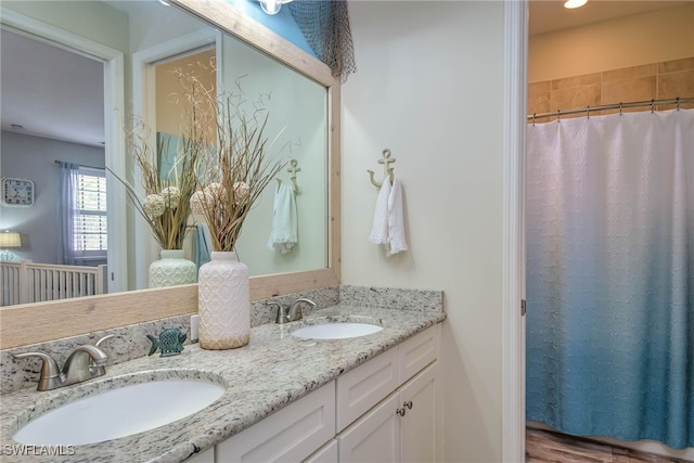 bathroom featuring a sink, curtained shower, and double vanity