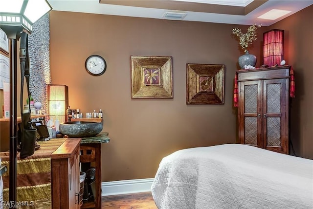 bedroom featuring wood finished floors, visible vents, and baseboards