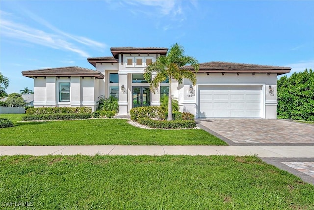 prairie-style home with a front yard, decorative driveway, a garage, and stucco siding