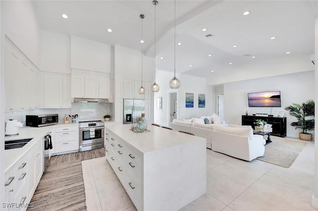 kitchen featuring white cabinets, appliances with stainless steel finishes, light countertops, and a high ceiling