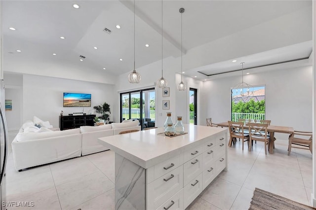 kitchen with visible vents, a kitchen island, light countertops, white cabinets, and open floor plan