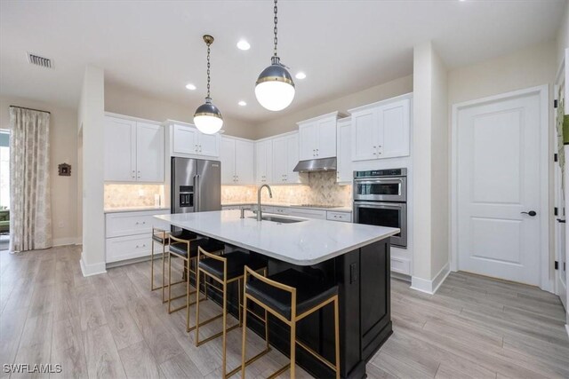 kitchen featuring visible vents, stainless steel appliances, a sink, light countertops, and under cabinet range hood