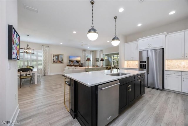 kitchen with backsplash, light countertops, white cabinets, stainless steel appliances, and a sink