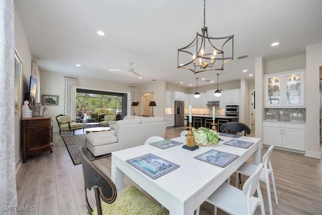 dining area featuring ceiling fan with notable chandelier, recessed lighting, light wood-style floors, and visible vents