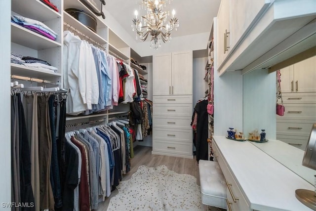 spacious closet with light wood-type flooring and an inviting chandelier