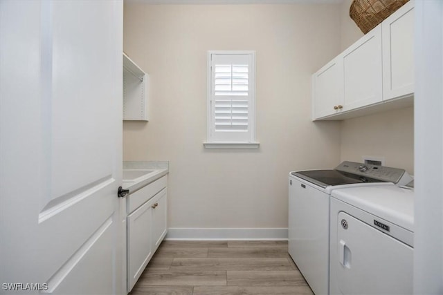 clothes washing area featuring cabinet space, baseboards, light wood finished floors, and washer and clothes dryer