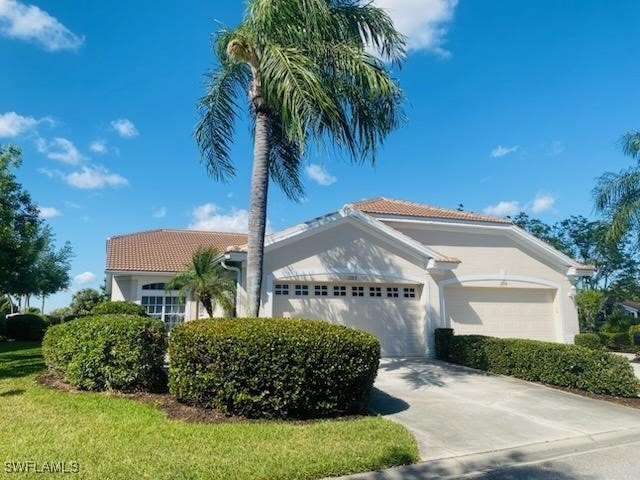 12713 Devonshire Lakes Dr, Fort Myers, FL 33913 - view of front facade with driveway, a garage, a tiled roof, and stucco siding