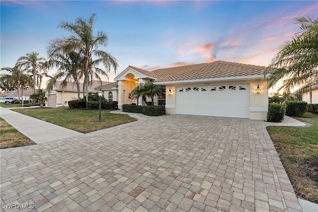 view of front of home featuring a tiled roof, decorative driveway, a garage, and stucco siding