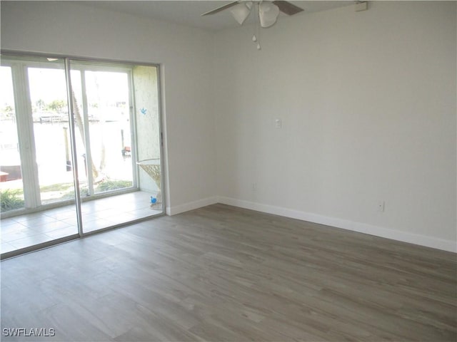 spare room featuring baseboards, ceiling fan, and wood finished floors