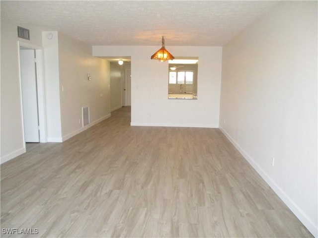 unfurnished room with visible vents, baseboards, a textured ceiling, and light wood finished floors