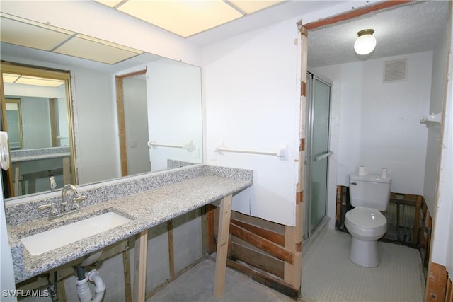 bathroom featuring visible vents, a stall shower, a sink, a textured ceiling, and toilet