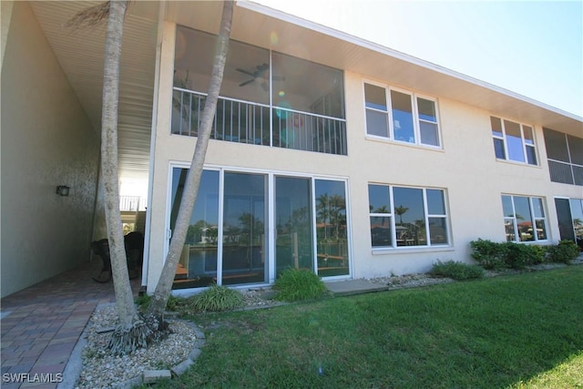 rear view of property featuring stucco siding and a lawn