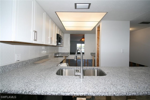 kitchen featuring a sink, visible vents, white cabinetry, and stainless steel microwave