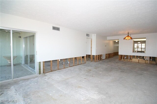 unfurnished room with visible vents, a textured ceiling, and concrete flooring