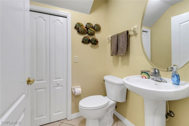 bathroom featuring a closet, tile patterned floors, toilet, and baseboards