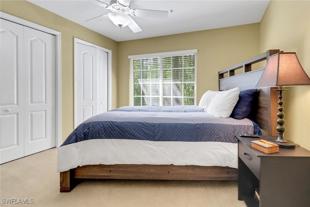 carpeted bedroom featuring a ceiling fan and multiple closets