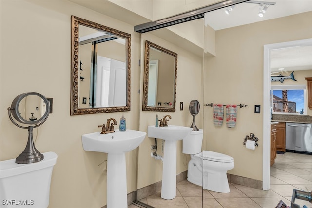 bathroom with tile patterned flooring, toilet, baseboards, and a sink