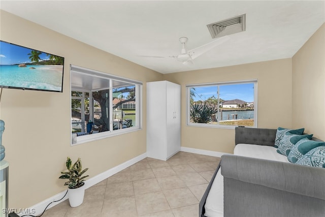 sitting room with light tile patterned floors, a ceiling fan, visible vents, and a wealth of natural light