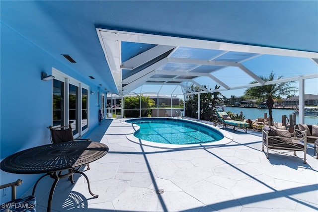 outdoor pool featuring glass enclosure, a patio, and a water view