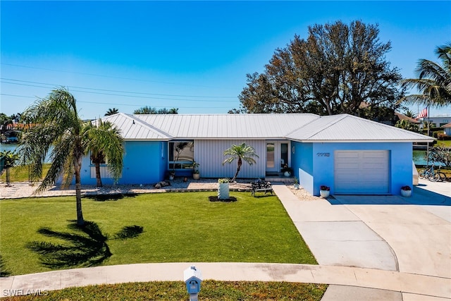 ranch-style home with an attached garage, stucco siding, a front lawn, concrete driveway, and metal roof