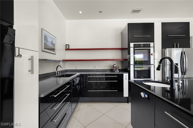 kitchen with dark countertops, dark cabinets, appliances with stainless steel finishes, and a sink