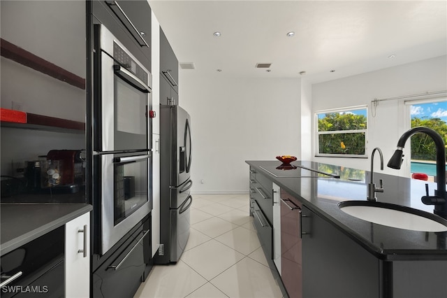 kitchen with visible vents, modern cabinets, a sink, dark countertops, and appliances with stainless steel finishes