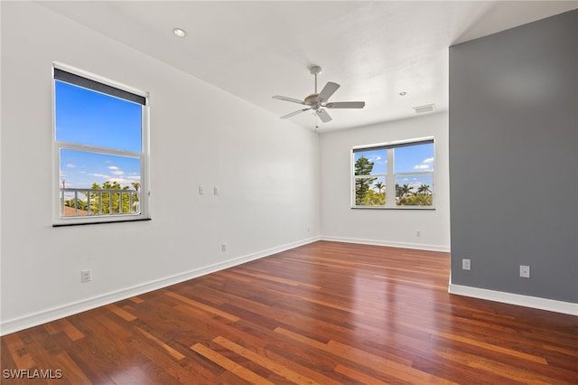 unfurnished room featuring plenty of natural light, visible vents, a ceiling fan, and wood finished floors