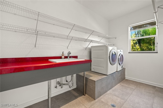laundry room featuring a sink, washing machine and dryer, light tile patterned floors, baseboards, and laundry area