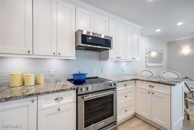 kitchen with white cabinetry, stainless steel appliances, a peninsula, decorative backsplash, and light stone countertops