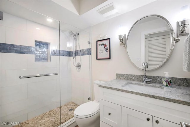 bathroom featuring vanity, a shower stall, toilet, and visible vents