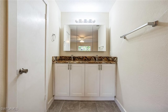 bathroom featuring a sink, baseboards, double vanity, and tile patterned floors