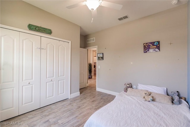 bedroom featuring light wood-style flooring, a ceiling fan, visible vents, and a closet