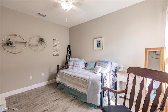 bedroom with a ceiling fan, visible vents, wood finished floors, and baseboards