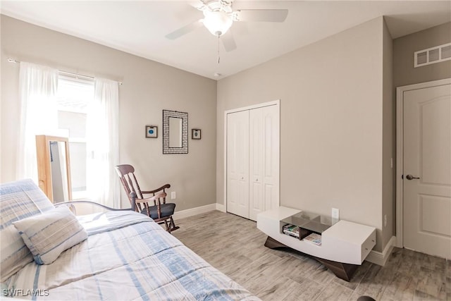 bedroom with light wood-type flooring, visible vents, baseboards, and a closet