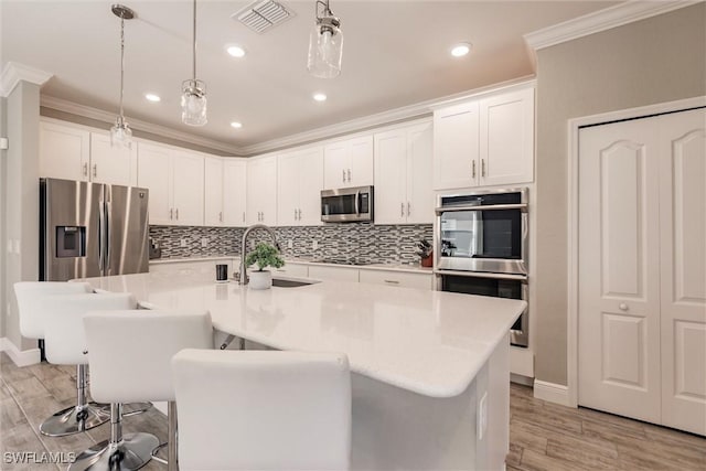 kitchen featuring visible vents, crown molding, stainless steel appliances, white cabinetry, and a sink