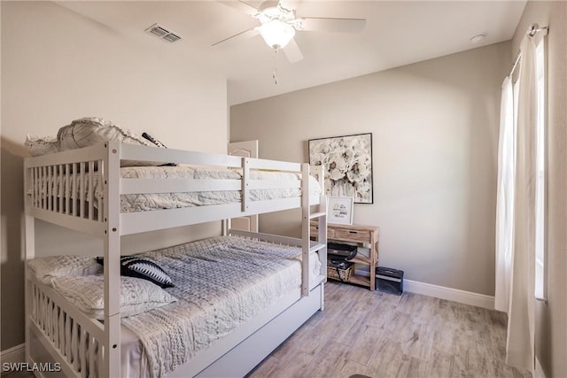 bedroom featuring ceiling fan, wood finished floors, visible vents, and baseboards