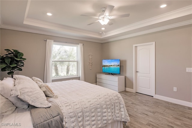 bedroom with a raised ceiling, ornamental molding, baseboards, and light wood-type flooring